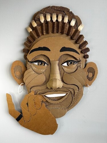 whimsical wall sculpture of a woman made with upcycled cardboard and found objects