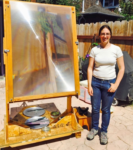 artist with large magnifying glass to melt glass